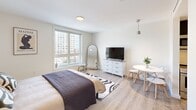 This efficiently designed 350 square foot apartment in Quincy, MA offers a harmonious blend of comfort and functionality. The space comprises one bedroom, one bathroom, and a well-appointed kitchen, all thoughtfully arranged on a single floor.

The bathroom showcases modern amenities, including a spacious shower with a curved curtain rod, a sleek vanity with ample storage, and an illuminated mirror. The light-colored tile flooring complements the overall bright aesthetic.

The bedroom, occupying a generous 200 square feet, features large windows that flood the space with natural light and offer urban views. The room is equipped with a comfortable bed, stylish nightstands, and a dresser that doubles as a TV stand. A full-length mirror and small seating area add practical touches.

The kitchen, while compact, is fully equipped with stainless steel appliances, including a refrigerator, stove, microwave, and dishwasher. Dark wood cabinetry contrasts beautifully with the light countertops and backsplash, creating a contemporary feel.

Throughout the apartment, light wood-look flooring unifies the space, while the crisp white walls enhance the sense of openness. Despite its modest size, the apartment's clever layout and thoughtful design elements create a surprisingly spacious and inviting home.
