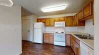 Located at 1996 County Rd D E in Maplewood, Minnesota, this single-floor unit offers a practical and well-organized layout. The kitchen is a standout feature, equipped with warm honey-toned wood cabinetry providing generous storage space, white appliances including a refrigerator, electric range, over-the-range microwave, and dishwasher, all complemented by light countertops and durable wood-look flooring. A pendant light adds a functional accent above the kitchen area.

The open living space transitions seamlessly from the kitchen and features plush carpeting underfoot, creating a comfortable and inviting atmosphere. A sliding glass door at the far end of the living area fills the room with natural light and provides outdoor access, contributing to an airy feel throughout.

The bathroom is thoughtfully appointed with earthy tile flooring, a full tub-shower combination, a vanity with wood cabinetry, and clean white fixtures. A dedicated in-unit laundry area with overhead cabinetry accommodates a full-size washer and dryer, adding significant convenience. The textured ceilings and neutral wall tones throughout the unit create a cohesive, understated aesthetic suitable for comfortable everyday living.