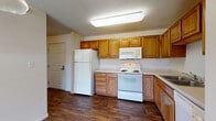 Located at 1996 County Rd D E in Maplewood, Minnesota, this single-floor unit offers a practical and well-organized layout. The kitchen is a standout feature, equipped with warm honey-toned wood cabinetry providing generous storage space, white appliances including a refrigerator, electric range, over-the-range microwave, and dishwasher, all complemented by light countertops and durable wood-look flooring. A pendant light adds a functional accent above the kitchen area.

The open living space transitions seamlessly from the kitchen and features plush carpeting underfoot, creating a comfortable and inviting atmosphere. A sliding glass door at the far end of the living area fills the room with natural light and provides outdoor access, contributing to an airy feel throughout.

The bathroom is thoughtfully appointed with earthy tile flooring, a full tub-shower combination, a vanity with wood cabinetry, and clean white fixtures. A dedicated in-unit laundry area with overhead cabinetry accommodates a full-size washer and dryer, adding significant convenience. The textured ceilings and neutral wall tones throughout the unit create a cohesive, understated aesthetic suitable for comfortable everyday living.