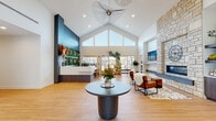 Located at 5302 S Champions Drive in Rogers, Arkansas, this single-story clubhouse is a thoughtfully designed community amenity facility offering a diverse range of spaces for work, fitness, and socializing. The building's centerpiece is a dramatic main lobby distinguished by soaring vaulted ceilings with clerestory windows that flood the space with natural light. A striking stone fireplace anchors one side of the room, while a bold teal accent wall frames the reception area. An eye-catching sculptural pendant light and light wood flooring complete the modern aesthetic.

Adjacent to the lobby, a fully equipped kitchen features floor-to-ceiling cabinetry in rich wood tones, stainless steel appliances, quartz countertops, and pendant lighting over a central island. The social lounge and game room offer pool and shuffleboard tables, large windows with outdoor views, and open space for gathering.

The fitness center is divided into two well-equipped zones: a cardio area with treadmills and mirrored walls, and a strength training zone with free weights, benches, cable machines, and exercise balls beneath vaulted ceilings. Dedicated coworking areas provide both collaborative conference-style seating and individual workstations with wall-mounted displays. A bright social dining room with round tables and large windows rounds out this versatile community space.