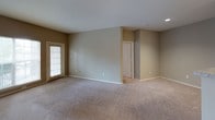 The Evergreen floor plan is a single-story, two-bedroom, two-bathroom residence with a well-organized layout designed for comfortable everyday living. The living area is carpeted and open, featuring neutral warm-toned walls, recessed lighting, and a sliding glass door that allows natural light to fill the space. A pass-through peninsula separates the living area from the kitchen, which is equipped with dark espresso cabinetry, granite-style countertops, and black appliances including a refrigerator, range, over-the-range microwave, and dishwasher. Wood-style flooring runs through the kitchen and entry area, providing a practical contrast to the plush carpet found throughout the rest of the unit.

Both bedrooms are carpeted and feature ceiling fans, natural light from windows with blinds, and neutral wall tones. Each bedroom is served by its own full bathroom, both finished consistently with dark espresso vanity cabinetry, granite-style countertops, a single-basin sink, wood-style tile flooring, and a tiled tub/shower combination. One bathroom includes a vanity mirror with overhead pendant lighting for added functionality. The overall aesthetic throughout the residence is cohesive, practical, and move-in ready.