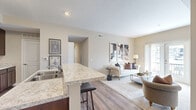 This single-floor residence at 4100 Lakeview Crossing in Columbus, Ohio offers four bedrooms and two full bathrooms within a thoughtfully designed layout. The open-concept kitchen and living area serves as the heart of the home, where rich dark-walnut cabinetry, light granite countertops, and black appliances define a well-appointed kitchen. A peninsula with bar seating provides additional functionality and naturally connects the kitchen to the living space, which features warm hardwood-style flooring throughout.

The living room is bright and inviting, benefiting from natural light that streams through a set of French doors opening onto a private balcony with outdoor views. Neutral, warm-toned walls carry consistently throughout the space, creating a cohesive and calming ambiance.

The four bedrooms are carpeted and feature neutral walls with natural light from individual windows. The primary bedroom offers a comfortable, well-proportioned retreat.

Both bathrooms are finished with matching dark cabinetry, granite-topped vanities, tile flooring, and framed mirrors, maintaining design consistency across the unit. A hallway connects the bedrooms and bathrooms efficiently. Overall, the unit presents a clean, modern aesthetic with practical and cohesive finishes throughout.