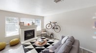 This single-floor residence offers a thoughtfully designed layout that balances modern style with everyday functionality. The open-concept kitchen is a standout feature, equipped with sleek dark gray cabinetry, a white subway tile backsplash, quartz countertops, and a full suite of stainless steel appliances. A peninsula counter with an integrated sink provides additional workspace and serves as a natural gathering point that connects the kitchen to the rest of the living area. The living room is bright and welcoming, featuring a tiled fireplace, large windows that invite natural light, and durable wood-style flooring that extends throughout the main areas. The bedroom is a comfortable retreat with plush carpeting, a spacious walk-in closet with built-in shelving and hanging rods, and sliding glass doors that open to an outdoor area. The full bathroom is cleanly finished with a wide vanity, quartz countertop, dark cabinetry, a large mirror, and a shower-tub combination. A dedicated in-unit laundry area houses a full-sized side-by-side washer and dryer with overhead shelving for storage. Neutral tones and modern finishes are carried consistently throughout, creating a cohesive and move-in-ready living environment.