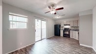 Located at 5341 Gawain Dr in San Antonio, TX, this 2-bedroom, 1-kitchen unit offers a practical and well-organized layout across a single floor. Wood-look laminate flooring runs throughout the space, providing a cohesive and easy-to-maintain surface in every room.

The kitchen is efficiently designed with gray cabinetry, a mosaic tile backsplash, gray countertops, and a full suite of black appliances including a gas range, refrigerator, and dishwasher. A textured ceiling and flush-mount lighting complete the kitchen's functional aesthetic.

The living area features a ceiling fan with light fixture, a built-in shelving unit ideal for storage or display, and direct access to the front entry. The neutral gray walls and laminate flooring create a bright, airy feel throughout.

The primary bedroom is a well-proportioned space with a ceiling fan, a large window that brings in natural light and outdoor views of surrounding greenery, and a textured ceiling. Additional storage is provided through a sliding-door closet with built-in shelving and a hanging rod. The second bedroom is similarly finished, maintaining the consistent style found throughout the unit. This residence offers a straightforward, move-in-ready living environment suited for a variety of lifestyles.