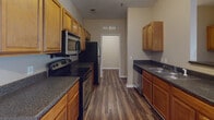 Located at 2100 McAndrew Dr in Raleigh, NC, this single-floor unit offers a well-designed, functional layout across multiple rooms. The open-concept living area is finished with rich, dark hardwood-style flooring and neutral warm-toned walls, creating a welcoming atmosphere. Ceiling fans are installed in the main living space and bedrooms, providing both comfort and air circulation. Windows throughout allow natural light to brighten the interior.

The kitchen is a standout feature, offering ample warm wood cabinetry, dark granite-style countertops, and stainless steel appliances including a range, microwave, refrigerator, and dishwasher. A peninsula counter provides additional workspace and a natural transition into the living area.

The bedrooms are carpeted for comfort and feature ceiling fans and windows with outdoor views. At least one bedroom includes a walk-in closet with built-in shelving, and an adjacent bathroom with a dark granite vanity is conveniently accessible.

The bathrooms are finished with matching dark hardwood-style flooring, rich wood vanities, and dark countertops. One bathroom includes a shower-tub combo, while another features a dedicated walk-in shower. The consistent finishes throughout give the space a cohesive and polished look.