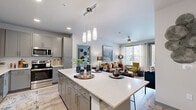 Located at 10655 Brightman Blvd in Jacksonville, FL, this thoughtfully designed 2-bedroom, 2-bathroom residence offers a functional and stylish single-floor layout. The open-concept kitchen and living area serves as the heart of the home, anchored by a large quartz-topped island with pendant lighting overhead. The kitchen features gray shaker cabinetry, a white tile backsplash, stainless steel appliances, and light wood-style flooring that extends throughout the space. The adjacent living room is bright and welcoming, with large windows and a glass door that invite natural light and offer outdoor views of the surrounding community. Both bedrooms are comfortably sized, with the primary bedroom providing a generous footprint, ceiling fan, and a large window with outdoor views. Each room is complemented by dedicated closets for ample storage. The two bathrooms are clean and modern, with one featuring a full soaking tub and light wood-tone flooring. A dedicated in-unit laundry area with a stacked washer and dryer adds everyday convenience. The overall ambiance is contemporary and bright, with a neutral color palette and cohesive finishes throughout.
