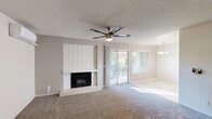 Located at 4835 N Cedar Ave in Fresno, CA, this one-bedroom, one-bathroom residence offers a thoughtfully arranged single-floor layout totaling approximately 670 square feet. The open living and dining area serves as the heart of the home, featuring plush wall-to-wall carpeting, a textured ceiling with a ceiling fan and integrated light fixture, and a striking white wood-paneled fireplace with a tile surround. Sliding glass doors flood the space with natural light and provide direct access to a private balcony with outdoor views. A pendant chandelier anchors the adjacent dining area, which flows seamlessly into the kitchen. The kitchen is well-appointed with warm wood cabinetry, light countertops, tile flooring, a dishwasher, electric range, and a full-size refrigerator, offering ample storage and prep space. The bedroom is a comfortable retreat with carpeted flooring, a ceiling fan, a wall-mounted mini-split unit for personalized climate control, and a window with outdoor views. Two closets provide generous storage throughout the unit. The bathroom includes a full tub and shower combo with tiled surround and tile flooring. A dedicated utility room and hallway complete the layout, adding practical functionality to this well-rounded Fresno residence.