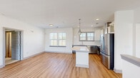 Located at 208 Windfall Way in Myrtle Beach, SC, this two-story home offers a well-designed layout spread across two floors. The main level hosts the majority of the living space, featuring an open-concept kitchen and living room that serves as the heart of the home. The kitchen is outfitted with stainless steel appliances—including a refrigerator, range with a wall-mounted hood vent, dishwasher, and microwave—complemented by quartz countertops, white upper cabinetry, gray lower cabinetry, a subway tile backsplash, and a central island. Light hardwood-style flooring runs throughout the main living areas, contributing to a bright, cohesive aesthetic. A set of French doors with a transom window opens to a small balcony, filling the living room with natural light. The shared bathroom features a dual-sink vanity with blue-gray cabinetry, a large framed mirror, and modern light fixtures. Both bedrooms are carpeted and receive ample natural light through double windows, each equipped with ceiling fans. The primary bedroom is generously sized with dedicated closet space. A small entry vestibule on the ground level leads upstairs, connecting all areas through well-placed hallways.