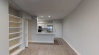 Located at 14501 Compass St in Corpus Christi, TX, this single-floor unit offers a thoughtfully designed open-concept layout finished with light wood-look flooring and a neutral gray palette throughout. The kitchen serves as the centerpiece of the living space, featuring white cabinetry, a tile backsplash, granite countertops with an undermount sink on a peninsula island, and a full suite of stainless steel appliances including a French door refrigerator, electric range, and microwave. Built-in open shelving adds convenient storage to the adjacent living area. The spacious living room is highlighted by a vaulted ceiling, ceiling fan, and French doors that invite natural light and provide outdoor access. Bedrooms are comfortably sized, each with light flooring and ceiling fans, including one room with a window overlooking the exterior. Two bathrooms continue the granite countertop theme with white cabinetry, framed mirrors, and brushed nickel fixtures. The primary bathroom offers a dual-sink vanity, while the secondary bathroom includes a tub-shower combination with marble-style tile surround. The overall ambiance is clean, modern, and move-in ready.