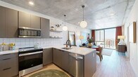 Located at 50 E Fillmore Ct in the heart of Phoenix, AZ, this modern one-bedroom, one-bathroom residence offers a thoughtfully designed open-concept layout with contemporary finishes throughout. The exposed concrete ceiling lends an industrial-chic character that carries through the entire space, complemented by warm light wood flooring.

The combined kitchen and living area serves as the heart of the home. The kitchen is outfitted with sleek gray cabinetry, white tile backsplash, stainless steel appliances including a refrigerator, range, microwave, and dishwasher, and a peninsula with a double sink and white countertops. Globe pendant lights add a stylish touch overhead. The living area transitions seamlessly from the kitchen and is bathed in natural light from expansive floor-to-ceiling windows that frame sweeping views of the Phoenix skyline.

The bedroom is a serene retreat featuring its own floor-to-ceiling window with city views, a ceiling fan, and generous closet space. The bathroom is finished with large-format white wall tiles, a walk-in glass shower, terrazzo-style flooring, and a warm wood vanity with black fixtures. A dedicated laundry area adds everyday convenience. This well-appointed urban residence is a compelling blend of modern design and functional living.