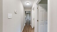 This single-floor, 2-bedroom, 2-bathroom home offers a thoughtfully designed layout with a clean, modern aesthetic throughout. Warm hardwood-style flooring flows seamlessly through all main living areas, complemented by neutral gray and white tones that create a bright, cohesive atmosphere.

The living room serves as the heart of the home, anchored by a classic white brick fireplace and a sliding glass door that invites natural light and provides access to an outdoor area. Adjacent to the living room, the dining area features a pendant light fixture, continuing the open and airy feel.

The galley-style kitchen is well-equipped, boasting white shaker cabinetry, granite-style countertops, a stainless steel sink, and a full suite of appliances including a refrigerator and electric range. A closet just off the kitchen provides additional storage.

The primary bedroom offers a comfortable footprint with neutral walls and hardwood-style flooring, accompanied by two walk-in closets fitted with wire shelving systems for organized storage. The second bedroom is equally well-sized and bright. Both bathrooms are clean and functional, with one featuring a full soaking tub and shower combo with brushed nickel fixtures.

A central hallway connects all rooms efficiently, and a dedicated laundry area adds everyday convenience to this well-rounded home.