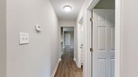 This single-floor, 2-bedroom, 2-bathroom home offers a thoughtfully designed layout with a clean, modern aesthetic throughout. Warm hardwood-style flooring flows seamlessly through all main living areas, complemented by neutral gray and white tones that create a bright, cohesive atmosphere.

The living room serves as the heart of the home, anchored by a classic white brick fireplace and a sliding glass door that invites natural light and provides access to an outdoor area. Adjacent to the living room, the dining area features a pendant light fixture, continuing the open and airy feel.

The galley-style kitchen is well-equipped, boasting white shaker cabinetry, granite-style countertops, a stainless steel sink, and a full suite of appliances including a refrigerator and electric range. A closet just off the kitchen provides additional storage.

The primary bedroom offers a comfortable footprint with neutral walls and hardwood-style flooring, accompanied by two walk-in closets fitted with wire shelving systems for organized storage. The second bedroom is equally well-sized and bright. Both bathrooms are clean and functional, with one featuring a full soaking tub and shower combo with brushed nickel fixtures.

A central hallway connects all rooms efficiently, and a dedicated laundry area adds everyday convenience to this well-rounded home.