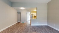 This single-floor residence offers a thoughtfully designed open-concept layout that seamlessly connects the living and kitchen areas. The main living space features durable wood-look vinyl flooring, neutral gray walls, and flush-mount ceiling lighting, creating a clean and inviting atmosphere throughout. A pass-through peninsula with granite countertops separates the living area from the kitchen, allowing for an open flow between the two spaces.

The kitchen is well-equipped with stainless steel appliances, including a refrigerator, range, and microwave. White shaker-style cabinetry provides ample storage, while a subway tile backsplash and granite countertops lend a modern, polished finish. A stainless steel sink completes the functional workspace.

The living area opens toward a hallway leading to a spacious room with vaulted ceilings, a large window, and two doors — offering a bright and airy feel with natural light filtering in. The bedroom is finished with plush carpet, a ceiling fan, and a full-width sliding glass door that brings in abundant natural light and outdoor views.

The bathroom features a granite-topped vanity, subway tile surrounding the bathtub and shower combination, and brushed nickel fixtures, tying together a cohesive and contemporary aesthetic across the entire residence.