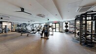 Located at 500 Parq Ln in Parsippany, NJ, this expansive fitness center offers a comprehensive, full-service workout facility across a single floor. The space is thoughtfully divided into distinct training zones, each designed to accommodate a wide range of fitness activities and exercise styles.

The main workout area features durable rubber flooring and is outfitted with an impressive array of cardio equipment, including ellipticals, treadmills, rowing machines, and stationary bikes, all arranged to maximize floor space and movement. A dedicated strength training zone houses a TKO multi-station cable and power rack system, along with cable machines and resistance equipment for a thorough full-body workout.

A separate functional training studio, accessible through sleek floor-to-ceiling glass sliding doors with black steel frames, features light hardwood flooring and organized wall-mounted shelving stocked with medicine balls, kettlebells, and stability balls. This area provides an ideal setting for dynamic, high-intensity training.

The entry area is finished with warm-toned rubber flooring, built-in wooden shelving for towels and accessories, and a ceiling fan, lending a welcoming and organized atmosphere. Large windows throughout the facility invite natural light and offer outdoor views, while ceiling-mounted HVAC units and multiple ceiling fans ensure a comfortable environment. The overall design is modern and functional, with a neutral color palette and thoughtful layout that supports a premium fitness experience.