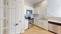 This two-story home is thoughtfully designed with functional living spaces spread across both floors. The main level features light hardwood-style flooring that flows through the common areas, including a well-appointed kitchen outfitted with white shaker cabinetry, light stone-look countertops, a tiled backsplash, and stainless steel appliances including an electric range and over-the-range microwave. A dedicated laundry room on this level includes a full-size washer and dryer and an overhead storage shelf, adding practical convenience.

A carpeted staircase with a handrail leads to the upper level, where the bedrooms are finished with plush carpet, neutral walls, and ceiling fans with lighting. One upper-level room features crown molding, a ceiling fan, and a glass-paned door that opens to an exterior access point, adding an elegant touch. Additional bedrooms offer natural light through windows with blinds. The bathrooms are clean and functional, each featuring tub/shower combinations with tiled surrounds, hardwood-style flooring, white cabinetry, and brushed nickel fixtures. Overall, the home presents a neutral, move-in-ready aesthetic throughout.
