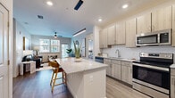This thoughtfully designed 2-bedroom, 2-bathroom residence features a contemporary open-concept layout that seamlessly connects the kitchen, dining, and living areas. The kitchen is a standout, boasting light wood cabinetry, a full suite of stainless steel appliances, a subway tile backsplash, and a generous granite-topped island with bar seating — ideal for both casual dining and entertaining. Recessed lighting and a sleek pendant fixture illuminate the space effectively.

The living room is bright and welcoming, featuring wood-style flooring, a ceiling fan, and large windows with an exterior door that invite abundant natural light and outdoor views. Both bedrooms are carpeted and comfortably sized, with the primary bedroom offering windows overlooking the surroundings and a dedicated walk-in closet with built-in wire shelving. The second bedroom provides a quiet, versatile retreat.

Each of the two bathrooms is finished with granite-topped wood vanities, framed mirrors, tile flooring, and glass-enclosed showers. A hallway connects the private areas of the residence, with two closets providing ample storage. The overall aesthetic is clean and modern, with neutral tones and quality finishes carried consistently throughout the home.