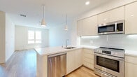 Located at 2968 W 7th St in Los Angeles, CA, this thoughtfully designed one-bedroom, one-bathroom unit offers a clean, modern aesthetic across its single floor. Light wood-tone flooring runs throughout, creating a cohesive and airy feel in every room.

The kitchen and living area share an open layout, with the kitchen featuring a full suite of stainless steel appliances — including a French door refrigerator, gas range, built-in microwave, and dishwasher. High-gloss cream cabinetry extends to the ceiling for ample storage, complemented by a subway tile backsplash and light quartz countertops.

The bedroom receives generous natural light through large windows that offer views of the surrounding neighborhood. The room connects directly to a dedicated closet with built-in shelving and hanging rods, offering well-organized storage. A separate walk-in closet provides additional space.

The bathroom is finished with large-format tile surrounding the soaking tub and shower, a modern floating vanity with a backlit mirror, and neutral tile flooring. The overall color palette — whites, creams, and soft naturals — reinforces a clean, contemporary ambiance throughout the unit.