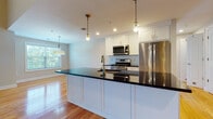 Located at 2-48 Grove Ave in Cedar Grove, NJ, this two-floor residence offers a thoughtfully designed layout with high-quality finishes at every turn. The main level showcases an open-concept kitchen and living area anchored by gleaming hardwood floors. The kitchen is equipped with stainless steel appliances, white shaker cabinetry, a subway tile backsplash, and a large center island topped with striking dark countertops, illuminated by stylish pendant lighting. The expansive living area benefits from abundant natural light streaming through large windows with views of the surrounding greenery. A staircase with classic wood railings connects the two floors. The upper level features carpeted bedrooms with generous windows that frame leafy outdoor views, providing a calm and comfortable retreat. Vaulted ceilings in select areas add architectural interest and a sense of openness. The bathrooms are finished with marble-style tile flooring and upscale fixtures; one includes a glass-enclosed walk-in shower with subway tile and brushed gold hardware, while another offers a soaking tub and dark vanity with a marble countertop. Recessed lighting throughout enhances the clean, modern aesthetic of this well-appointed Cedar Grove residence.