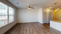 Located at 1133 Commerce Dr in Decatur, GA, this single-floor unit offers a well-designed layout that balances modern finishes with functional living spaces. The kitchen serves as a standout feature, showcasing light-toned flat-front cabinetry, granite countertops, a sleek tile backsplash, and a full suite of stainless steel appliances including a French door refrigerator with ice maker, electric range, built-in microwave, and dishwasher. Rich hardwood-style flooring flows throughout the main living areas, lending warmth and continuity to the space. The living area is bright and open, benefiting from natural light through a window with blinds and a ceiling fan overhead, providing both comfort and airflow. A louvered closet door adds a classic touch to the room's understated design. The bathroom features a tub-shower combination with clean white subway tile surround and brushed gold fixtures, complemented by a well-lit vanity with ample counter space. Adjacent to the bath, a carpeted walk-in closet with wire shelving offers generous storage. The overall aesthetic is clean and contemporary, making this Decatur residence a polished and practical space.