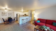 This single-floor residence offers a thoughtfully designed layout that balances open communal spaces with comfortable private areas. The open-concept living and kitchen area serves as the heart of the home, where the kitchen stands out with crisp white shaker-style cabinetry, granite-look countertops, stainless steel appliances including a range, microwave, and refrigerator, and a breakfast bar with seating for two. Wood-look flooring flows throughout the main living areas, lending a clean and cohesive aesthetic. Adjacent to the kitchen, the living room is bright and welcoming, featuring a sliding glass door that opens to a private balcony, filling the space with natural light and outdoor views. A dedicated dining area with ceiling fan provides an ideal setting for meals and gatherings. Both bedrooms are comfortably sized, finished with plush carpeting and ceiling fans, with one bedroom featuring a large window that enhances natural light. The two bathrooms are well-appointed with white cabinetry, granite-look vanity tops, and wood-look flooring. One bathroom includes a walk-in shower, while the other offers additional storage and a full vanity setup. Together, the rooms create a functional and inviting living environment throughout.