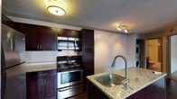Located at 1021 Everett Ave in Louisville's 40204 zip code, this single-floor residence offers a thoughtfully designed layout with quality finishes throughout. Dark hardwood flooring flows through the main living areas, creating a warm and cohesive aesthetic complemented by crown molding and neutral-toned walls.

The kitchen is a standout feature, showcasing rich dark-stained cabinetry, granite countertops, a classic white subway tile backsplash, and a full suite of stainless steel appliances including a double oven range and over-the-range microwave. A peninsula with an undermount sink and additional seating potential anchors the space, opening naturally toward the living and dining areas.

The living area benefits from large windows that invite natural light, while a wall-mounted mini-split system ensures efficient climate control year-round. A stacked washer and dryer unit is conveniently integrated into the main living space.

The bedroom features plush carpeting, a ceiling light fixture, and a window with outdoor views. The bathroom is cleanly finished with white subway tile surrounding the tub and shower, accented by a decorative mosaic tile inlay, and complemented by brushed nickel fixtures throughout.

Overall, the space presents a clean, modern interior with practical amenities in a well-established Louisville neighborhood.