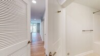 Located at 2801 E Main St in Richmond, VA, this single-floor, two-bedroom, two-bathroom unit offers a clean, modern aesthetic with thoughtful design details throughout. Light-toned hardwood flooring runs continuously across the living areas, complemented by crisp white walls and recessed lighting that create a bright, welcoming ambiance.

The open-plan kitchen and living room serve as the heart of the unit. The living area features large French doors with transom windows above, allowing generous natural light and outdoor views. A ceiling fan adds comfort, and built-in shelving provides practical storage. The kitchen is well-appointed with white shaker cabinetry, gray quartz countertops, stainless steel appliances including a refrigerator and range, and a undermount sink with brushed nickel fixtures.

A hallway lined with a louvered closet door connects the main living space to the bedrooms. Both bedrooms feature light hardwood floors, ceiling fans, and ample natural light. The primary bedroom includes access to a dedicated closet. Each bathroom is finished with white subway tile surrounding a soaking tub and shower combination, brushed nickel hardware, and light tile flooring. Additional conveniences include a dedicated laundry area, a utility room, and two closets, making this a highly functional and move-in-ready residence.