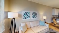 Located at 850 Arbor Way in Blue Bell, Pennsylvania, this well-appointed single-floor residence offers a thoughtfully designed layout that balances modern aesthetics with functional living. The open-concept kitchen is a standout feature, showcasing crisp white shaker cabinetry, a marble-inspired tile backsplash, sleek gray quartz countertops, and a full suite of stainless steel appliances including a gas range, built-in microwave, dishwasher, and French door refrigerator. Pendant lighting and track lighting illuminate the space, while light hardwood flooring adds warmth throughout. The living area is bathed in natural light from a large window overlooking greenery, creating a welcoming and airy ambiance. Contemporary geometric artwork adorns the neutral-toned walls, complementing the comfortable, neutral furnishings. The bedroom is a serene retreat, featuring plush carpeting, a large upholstered headboard, and a wide window that invites outdoor views and natural light. A walk-in closet provides generous storage, while the en-suite bathroom impresses with a floor-to-ceiling tiled glass-enclosed shower finished in polished chrome hardware. An in-unit washer is also present, adding everyday convenience to this refined and move-in-ready residence.