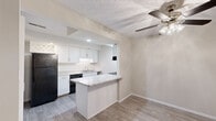 Located at 1818 Hemlock Ln in Elkhart, Indiana, this single-floor unit offers a thoughtfully arranged layout with a clean, updated aesthetic throughout. The kitchen serves as a central highlight, featuring crisp white shaker-style cabinetry, light granite countertops, and black appliances including a refrigerator, electric range, and dishwasher. A peninsula with a beadboard base and matching granite surface extends into the adjacent living area, creating a natural separation between the kitchen and main living space while also providing additional prep and seating space. Light wood-look flooring runs through the kitchen, complementing the neutral walls and bright recessed lighting.

The living area is generously sized, finished with plush carpet and a ceiling fan, and features a sliding glass door that opens to an outdoor green space, filling the room with natural light. A textured ceiling adds subtle character to this space. The bedrooms are carpeted and well-proportioned, with large windows that bring in outdoor views and natural light. One bedroom features dual closets, offering notable storage capacity. Additional rooms with carpet flooring provide flexible living arrangements. Throughout, the unit maintains a neutral, light color palette that creates a clean and cohesive atmosphere.