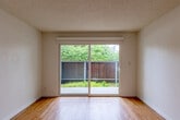 Located at 222 Columbia St in Santa Cruz, California, this 2-bedroom, 2-bathroom residence offers a practical and well-appointed single-floor layout. The open living area is bright and airy, featuring warm hardwood-style flooring and a ceiling fan, with a sliding glass door that leads directly to a private outdoor patio surrounded by greenery. The galley-style kitchen is efficiently designed with light maple cabinetry, dark countertops, stainless steel appliances including a dishwasher and refrigerator, a built-in microwave, and track lighting overhead. An in-unit washer is conveniently integrated within the kitchen space. The combined dining and kitchen area flows seamlessly into the living room, creating a cohesive and functional shared space. Both bedrooms are carpeted and filled with natural light from large windows offering views of the surrounding landscaping. The primary bedroom is generously sized and features a mirrored sliding-door closet with built-in shelving. Each bathroom is finished with wood-toned vanity cabinetry, dark countertops, and hardwood-style flooring. One bathroom includes a walk-in shower, while the other offers a full tub-shower combination. The overall ambiance is clean, neutral, and move-in ready.