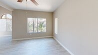 Located in Phoenix, AZ, this single-story, 3-bedroom, 3-bathroom home offers a thoughtfully designed layout with modern finishes throughout. Light wood-style tile flooring runs through the main living areas, complemented by neutral warm-beige walls and clean white trim that create a bright, cohesive aesthetic.

The open kitchen is a standout feature, boasting soaring ceilings, contemporary taupe cabinetry, crisp white countertops, and black appliances including a range and refrigerator. A peninsula provides additional prep space and flows naturally into the combined dining area. Large windows throughout the home invite abundant natural light and frame views of the surrounding Phoenix landscape, including mature palm trees.

The living room is spacious and airy, featuring a ceiling fan and multiple windows fitted with vertical blinds. Each of the three bedrooms is carpeted for comfort and includes ceiling fans and dedicated closet space, with the primary bedroom offering an en-suite bath and a walk-in closet with built-in shelving. The bathrooms are finished with matching cabinetry and light countertops, maintaining the home's consistent modern style. A hallway connects the bedrooms, adding to the home's functional flow. This residence offers a clean, move-in-ready environment well-suited to the sunny Phoenix lifestyle.