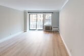 Located at 83-33 118th St in the charming Kew Gardens neighborhood of Queens, New York, this thoughtfully updated unit offers a clean, modern aesthetic throughout its single-floor layout. The spacious living area is a standout feature, showcasing light-toned wood flooring, crown molding, and a large sliding glass door that invites generous natural light and provides views of the surrounding neighborhood. A wall-unit air conditioner and radiator ensure year-round comfort.

The galley-style kitchen is efficiently designed with white cabinetry, dark granite countertops, a subway tile backsplash, and stainless steel appliances including a gas range and microwave. A window above the sink brings in additional natural light.

The bedroom is a quiet, well-proportioned room finished with the same light wood flooring and neutral gray walls. A window with neighborhood views and individual climate control units complement the space.

The bathroom features classic white subway tile walls, dark floor tiles, a tub-shower combination with glass enclosure, a modern vanity with mirror, and a small window for ventilation. Throughout the unit, crisp white trim, neutral wall tones, and consistent flooring create a cohesive and move-in-ready environment well-suited for urban living.