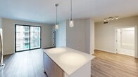 Located at 500 N Andrews Ave in the heart of Fort Lauderdale, FL, this well-appointed one-bedroom, one-bathroom residence offers a thoughtfully designed open-concept layout with modern finishes throughout. Wood-look flooring flows seamlessly across the living spaces, complementing the clean, neutral palette that defines the unit's contemporary aesthetic.

The kitchen is a standout feature, showcasing flat-front white cabinetry extending to the ceiling, a marble-inspired tile backsplash, stainless steel appliances including a refrigerator, range, microwave, and dishwasher, and a central island with a quartz countertop topped by elegant pendant lighting. The open layout connects the kitchen directly to the living area, which benefits from natural light and access to a private balcony through floor-to-ceiling sliding glass doors.

The spacious primary bedroom features a tray ceiling detail, hardwood-style flooring, and large windows that invite natural light. A dedicated walk-in closet with wire shelving provides generous storage. The bathroom is finished with large-format marble-look tile, a soaking tub with an overhead shower, a backlit vanity mirror, and a clean white quartz vanity surface. This unit combines functional design with upscale finishes in a prime South Florida location.