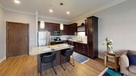 Located on 160th Street West in Lakeville, Minnesota, this single-floor residence offers a thoughtfully designed open-concept layout that seamlessly connects the kitchen, dining, and living areas. The kitchen is a standout feature, showcasing rich dark-stained cabinetry that extends to the ceiling, a classic white subway tile backsplash, and gleaming granite countertops. A central island with bar seating serves as both a functional workspace and a casual gathering spot, illuminated by stylish pendant lights overhead. Stainless steel appliances, including a refrigerator, range, microwave, and dishwasher, complete the well-equipped culinary space.

The living area flows naturally from the kitchen, finished with light hardwood-style flooring and soft, neutral wall tones that create a calm and inviting atmosphere. A large window allows natural light to brighten the room, offering views of the surrounding exterior grounds. The bedroom continues the serene palette, featuring plush carpeting and generously sized windows that frame outdoor views and fill the space with daylight. The bathroom is appointed with a granite-topped vanity, a dark-framed mirror, and clean, modern fixtures that maintain a cohesive design throughout the home.