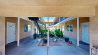 Located at 598 N Walton Ave in Yuba City, California, this multi-unit property is built around a central open-air courtyard that serves as the heart of the complex. The building's warm stucco exterior is finished in a distinctive golden-yellow tone, lending the property a welcoming and cohesive appearance. The courtyard is generously landscaped with mature trees, agave plants, and a variety of potted and ground-level plantings, creating a lush, shaded outdoor environment bathed in natural California sunlight.

The property features covered ground-floor walkways supported by structural posts, providing sheltered access to individual unit entrances. White entry doors line both the ground level and the upper floor, each accessible via a central staircase. The upper level is lined with decorative lattice-style balcony railings in a deep blue-black finish, adding an architectural accent that contrasts with the warm exterior tones. A no-smoking policy is posted throughout the shared courtyard areas.

The elongated layout of the building, as seen in the 3D model, reveals a well-organized structure with units accessible from the interior courtyard on both levels. The combination of mature landscaping, covered walkways, and open communal space makes this property a distinctive multi-unit offering in the Yuba City area.
