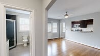 Located at 210 Rhode Island Ave NE in Washington, DC, this one-bedroom, one-bathroom unit offers a well-designed layout across a single floor. The combined kitchen and living area serves as the heart of the home, featuring warm hardwood flooring, soft grey walls, and a ceiling fan with a light fixture that enhances airflow and illumination. A distinctive private exterior door flanked by two windows floods the living space with natural light, creating a bright and welcoming atmosphere. The kitchen is thoughtfully appointed with rich dark espresso cabinetry, granite countertops, a white subway tile backsplash, and a full suite of stainless steel appliances including a range, microwave, dishwasher, and refrigerator. An in-unit washer is also conveniently tucked into the kitchen area. The bedroom is a comfortable retreat with gleaming hardwood floors, a ceiling fan, a wall-mounted split HVAC unit for individualized climate control, and windows that invite natural light. The bathroom features a corner walk-in shower with glass doors, a window for ventilation, and tiled flooring. A hallway and closet complete the thoughtful layout of this efficiently designed urban residence.