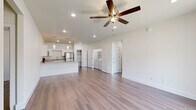 This single-story unit on SW Starling Lane in Bentonville, Arkansas, presents a clean, modern design defined by a neutral white palette and wood-look flooring that flows consistently throughout the space. The open-concept living and kitchen area serves as the heart of the home, where recessed lighting and ceiling fans maintain a bright, comfortable atmosphere. The kitchen is well-equipped with stainless steel appliances—including a refrigerator, range, microwave, and dishwasher—complemented by white shaker-style cabinetry, granite countertops, and a kitchen island that provides additional workspace and storage. A dedicated pantry alcove with built-in shelving adds practical storage directly off the kitchen. An in-unit laundry area is conveniently located within the main living space, housing a full-size washer and dryer with overhead shelving. The bedrooms are generously proportioned, each featuring ceiling fans and natural light from windows. One bedroom includes a spacious walk-in closet with multiple hanging rods and shelving. The bathrooms are finished with granite vanity tops, white cabinetry, and large mirrors, with one bathroom offering a tub-shower combination.