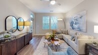 Located at 1100 Hampton Rivers Rd in Charleston, SC, this single-floor residence offers a well-designed, open-concept layout that seamlessly connects the kitchen, dining, and living areas. The kitchen is a standout feature, equipped with crisp white shaker-style cabinetry, stainless steel appliances including a range, microwave, dishwasher, and a large side-by-side refrigerator, all complemented by a two-tone island with a bright white countertop and navy blue base beneath stylish pendant lighting. Wood-look flooring flows through the main living areas, adding warmth and continuity throughout the space. The living room is bright and inviting, with multiple windows offering lush outdoor views and a ceiling fan overhead. A dedicated dining nook provides additional flexibility for everyday living. The bedrooms are carpeted for comfort, each featuring ceiling fans, ample natural light from large windows with outdoor views, and a calm, neutral color palette. The bathroom is well-appointed with white cabinetry, a full vanity, and a tub-shower combination, all finished with wood-look flooring. Throughout the residence, a consistent soft gray and white color scheme creates a clean, cohesive aesthetic that is both modern and welcoming.