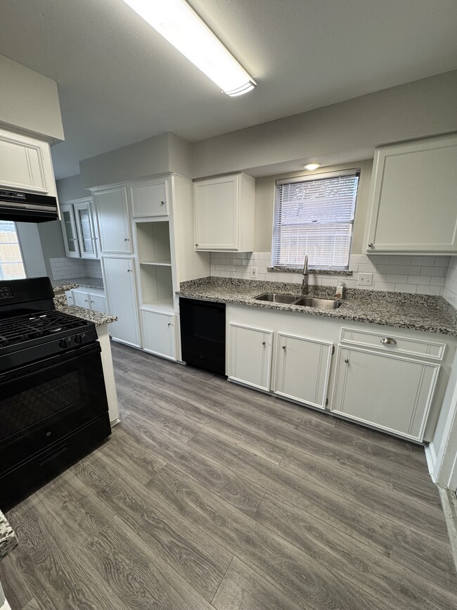 Functional kitchen with granite counters, white cabinets, and black appliances. - 11927 Troulon Dr