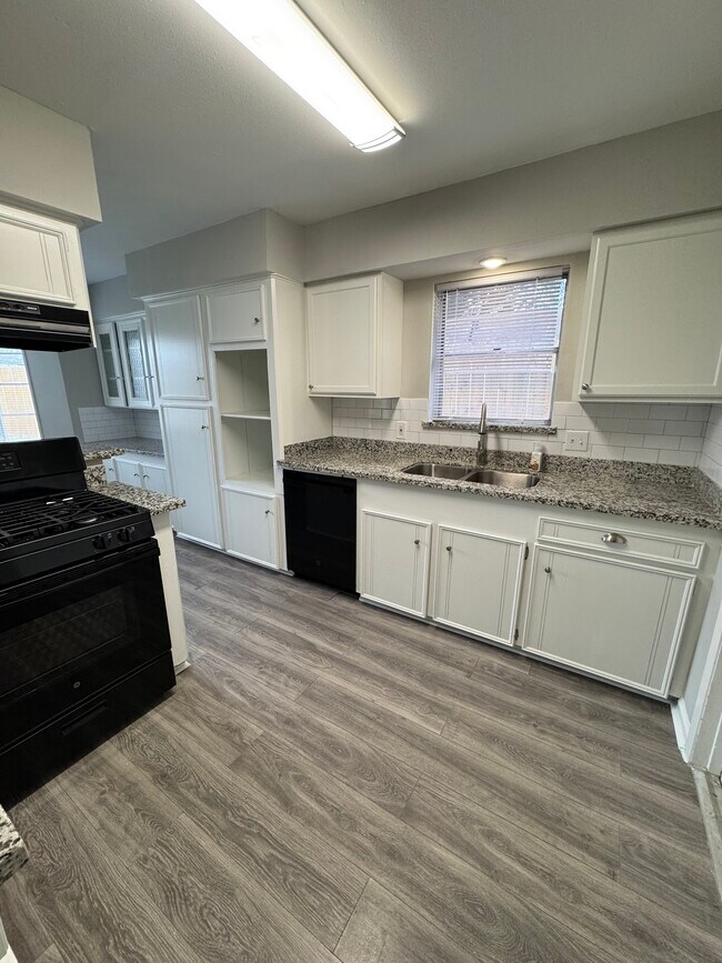 Functional kitchen with granite counters, white cabinets, and black appliances. - 11927 Troulon Dr House