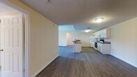 This single-floor residence offers a thoughtfully organized layout that balances open communal areas with comfortable private spaces. The living area flows seamlessly into the kitchen, which is outfitted with white cabinetry, dark stone-style countertops, wood-look vinyl flooring, and a full suite of appliances including a refrigerator, electric range, built-in microwave, and dishwasher. A peninsula counter adds additional workspace and provides a natural division between the kitchen and the open living space.

The bedrooms are generously proportioned, each featuring soft wall-to-wall carpet, warm neutral paint tones, and vertical blinds over large windows that bring in ample natural light. One bedroom includes a sliding glass door offering outdoor access, while another features a ceiling fan for added comfort. The rooms provide a calm, versatile backdrop suitable for a variety of furniture arrangements.

The bathrooms are clean and functional. One features a full bathtub and shower with white tile surround, while another offers a long vanity with a stone-topped counter, an undermount sink, white cabinetry, and tile flooring. Textured ceilings are consistent throughout, contributing to the unit's understated, practical character. Overall, this space presents a move-in-ready environment with a neutral palette and well-maintained finishes throughout.