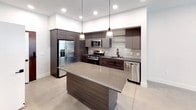 Located at 1921 Union St in Anaheim, California, this modern single-floor residence showcases a clean, contemporary design with polished concrete flooring, crisp white walls, and dark wood-toned cabinetry that flows consistently throughout the space.

The kitchen serves as a standout feature, offering a large center island with a quartz-style countertop, pendant lighting, and a full suite of stainless steel appliances including a gas range, microwave, dishwasher, and a side-by-side refrigerator with an ice and water dispenser. Sleek, flat-front dark cabinetry and a subway tile backsplash complete the contemporary aesthetic. Recessed lighting illuminates the space with a bright, functional ambiance.

The living area is open and generously proportioned, with a ceiling fan overhead and a view toward the kitchen's built-in cabinetry display. The bedroom features dual windows fitted with blinds that invite natural light, complemented by a ceiling fan for comfort. An adjoining walk-in closet provides practical storage with multiple wire shelving tiers.

The bathroom is elegantly appointed with a dual-sink vanity featuring dark wood cabinetry, matte black hardware, and mirrors with built-in lighting. A soaking tub with white subway tile surround rounds out the refined design. In-unit laundry with a stacked washer and dryer is conveniently tucked behind a louvered closet door in the kitchen area.