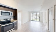 Located at 22555 SW 107th Ave in Miami, FL, this well-appointed three-bedroom, two-bathroom single-floor residence offers a clean, modern aesthetic throughout. Light wood-style flooring flows seamlessly across every room, complementing the bright white walls and creating a cohesive, contemporary atmosphere.

The open-concept living and dining area is anchored by large sliding glass doors that invite abundant natural light and provide views of the outdoors. The kitchen is thoughtfully designed with dark wood cabinetry extending to the ceiling, granite countertops, a subway tile backsplash, and a full suite of stainless steel appliances including a refrigerator, range, microwave, and dishwasher. Track lighting adds a modern touch overhead.

Each of the three bedrooms features large windows with horizontal blinds that frame lush outdoor greenery, keeping the spaces bright and airy. The primary bedroom includes a dedicated closet, while additional bedrooms offer built-in wardrobe storage with sleek, modern hardware.

Both bathrooms are finished with granite-topped dark vanities, large mirrors with bar lighting, and light wood-style flooring. One bathroom features a full tub-shower combination. The home also includes a dedicated laundry area, utility room, and ample closet storage throughout, rounding out a practical and polished living space.