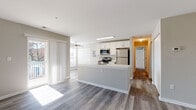 This single-floor residence offers a thoughtfully designed open-concept layout that seamlessly connects the kitchen and living areas. The kitchen serves as the centerpiece, featuring a large peninsula with a white quartz countertop, white shaker-style cabinetry, and a full suite of stainless steel appliances, including a refrigerator, range, microwave, and dishwasher. Wood-style plank flooring runs throughout the main living area, adding warmth and continuity to the space.

The living area is generously sized, with natural light streaming in through large windows fitted with horizontal blinds and sliding glass doors that open to an exterior space. A ceiling fan adds comfort to the room. Built-in closet storage is conveniently located within the living area.

The bedroom is carpeted and bright, featuring dual windows that bring in ample natural light. The bathrooms are finished with white vanities topped with light countertops, framed mirrors, brushed nickel fixtures, and tile flooring. One bathroom includes a walk-in shower with elegant marble-style tile surround, while the other features additional dual-mirror vanity lighting. A hallway connects the private areas of the unit, offering a well-organized and functional flow throughout.