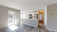 This single-floor residence offers a thoughtfully designed open-concept layout that seamlessly connects the kitchen and living areas. The kitchen serves as the centerpiece, featuring a large peninsula with a white quartz countertop, white shaker-style cabinetry, and a full suite of stainless steel appliances, including a refrigerator, range, microwave, and dishwasher. Wood-style plank flooring runs throughout the main living area, adding warmth and continuity to the space.

The living area is generously sized, with natural light streaming in through large windows fitted with horizontal blinds and sliding glass doors that open to an exterior space. A ceiling fan adds comfort to the room. Built-in closet storage is conveniently located within the living area.

The bedroom is carpeted and bright, featuring dual windows that bring in ample natural light. The bathrooms are finished with white vanities topped with light countertops, framed mirrors, brushed nickel fixtures, and tile flooring. One bathroom includes a walk-in shower with elegant marble-style tile surround, while the other features additional dual-mirror vanity lighting. A hallway connects the private areas of the unit, offering a well-organized and functional flow throughout.