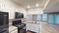 Located at 5680 Hibernia Dr in Columbus, Ohio, this single-floor, one-bedroom, one-bathroom unit offers a well-organized layout with a practical mix of hard flooring and plush carpet throughout. The kitchen and living area share an open, connected layout, with the kitchen showcasing white cabinetry, granite-look countertops, a double-basin stainless steel sink, and a full suite of black appliances including a gas range, over-the-range microwave, and refrigerator. Recessed lighting illuminates the kitchen, which also benefits from natural light through a window with vertical blinds. The living area is carpeted and features a sliding glass door flanked by a window, both dressed with vertical blinds, allowing ample natural light and outdoor views. The spacious primary bedroom includes soft carpeting, a ceiling fan with light fixture, and a window that brings in natural light. A hallway connects the main living spaces to the bathroom and a dedicated in-unit laundry area, which houses a full-size washer and dryer. Louvered closet doors and warm wood-toned interior doors add classic character throughout. The bathroom area features a vanity with storage. Wood-look hard flooring runs through the kitchen, hallway, and laundry areas, providing a cohesive and easy-to-maintain surface.
