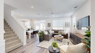 Located on Oleander Street in Lancaster, CA, this contemporary two-story home offers a thoughtfully designed layout spread across two floors. The main level opens into a bright, open-plan living room and kitchen area, where light wood-look flooring, recessed lighting, and a ceiling fan create a welcoming atmosphere. Large windows invite abundant natural light throughout, and the seamless flow between the living and dining areas makes the space ideal for both everyday living and entertaining. The kitchen is outfitted with white shaker cabinetry, light quartz countertops, stainless steel appliances, and a central island, all complemented by clean, modern finishes. A dedicated laundry room with a stacked washer and dryer adds everyday convenience. The upper floor hosts three bedrooms, including a well-sized primary bedroom with carpet flooring, a ceiling fan, and ample natural light. A versatile office with a sliding door opening to an outdoor area provides an ideal work-from-home space with outdoor views. Additional bedrooms are bright and comfortable, with one featuring bunk bed accommodations. Six bathrooms serve the home throughout, ensuring flexibility for residents and guests. Connecting hallways maintain a clean, neutral palette that ties the home's cohesive modern aesthetic together.