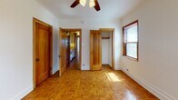 Located in Chicago's desirable Lincoln Park neighborhood, this single-floor unit at 2738 N Pine Grove Ave showcases classic architectural character throughout. The space is unified by rich parquet wood flooring that extends across every room, adding warmth and a timeless aesthetic to the interior.

The living areas are generously proportioned, each equipped with ceiling fans and natural light filtering through wood-trimmed windows fitted with blinds. Cast-iron radiators in multiple rooms speak to the building's vintage charm while providing reliable heating. Crown molding accents the ceilings, adding a refined architectural detail consistent throughout the unit.

The bedrooms are well-sized, each featuring closets with wood-framed doors that complement the overall warm, classic palette. Wall sconces provide ambient lighting, and the layout allows for a practical flow between rooms. A galley-style kitchen is visible from the bedroom corridor, outfitted with white appliances and cabinetry.

The bathroom continues the classic aesthetic with full white tile surround, a pedestal sink, a combined tub and shower, and a wood-framed medicine cabinet mirror. Clean and functional, it reflects the consistent design language found throughout the unit.

Overall, this space offers a cohesive, character-rich interior with durable finishes and traditional Chicago residential charm.