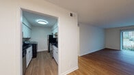 This single-floor residence offers a clean, modern aesthetic carried consistently throughout its well-organized layout. The living area is bright and open, featuring warm wood-look flooring and a sliding glass door fitted with vertical blinds that provides direct access to an outdoor space while allowing natural light to fill the room. The open sightlines from the living area connect seamlessly to adjacent spaces, creating a cohesive flow.

The galley-style kitchen is thoughtfully appointed with white shaker cabinetry, dark granite-style countertops, and a subway tile backsplash. It includes a stainless electric range, a black refrigerator, an overhead range hood, and a built-in washer and dryer unit, making laundry highly convenient. Overhead flush lighting keeps the kitchen well-illuminated.

The bedrooms feature the same wood-look flooring, white walls, and ample natural light from windows. At least one bedroom includes a closet with bifold doors and a hanging rod for organized storage.

The bathroom is finished with large-format marble-look tile flooring, a white subway tile tub surround, chrome fixtures, and a dark-topped vanity, presenting a clean and contemporary feel throughout.