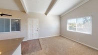 Located at 425 Merrimac Way in Costa Mesa, California, this single-floor residence offers a well-organized layout with a cohesive, neutral design palette throughout. The living area is a standout feature, showcasing vaulted ceilings with exposed white-painted wood beams that add architectural character and a sense of openness. Plush carpeting covers the main living and bedroom areas, while wood-look flooring defines the entryway and kitchen zones, providing a practical and stylish transition between spaces. Natural light enters through windows fitted with white horizontal blinds, brightening the warm beige-toned walls.

The kitchen is thoughtfully updated, featuring stainless steel appliances including a gas range and over-the-range microwave, white cabinetry, and a classic white subway tile backsplash that adds a clean, modern touch. The countertops and wood-look flooring complete the functional yet attractive kitchen space.

The bedroom continues the vaulted beamed ceiling design seen in the living area, maintaining a consistent architectural style. The bathroom includes a full-size tub and shower combination with clean white surround panels and a standard toilet, offering straightforward, functional amenities. Overall, the space presents a move-in ready interior with updated finishes in a well-located Costa Mesa community.