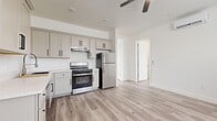 This single-story, 3-bedroom, 2-bathroom home offers a thoughtfully designed layout that maximizes both functionality and comfort. The open-concept kitchen and living area serves as the heart of the home, featuring gray shaker-style cabinetry with sleek black hardware, white countertops, and a full suite of stainless steel appliances including a gas range and refrigerator. Light wood-tone flooring runs throughout, complemented by a neutral white palette that gives the entire space a clean, modern feel. Ceiling fans provide additional airflow in key areas.

The primary bedroom is generously sized and includes direct access to a bathroom, offering added privacy. All bedrooms are bright and airy, benefiting from natural light through slatted blinds. Two closets provide ample storage, including a walk-in closet outfitted with shelving and hanging rods.

Both bathrooms are finished with white shaker vanities, white countertops, and glass-door shower enclosures, maintaining a consistent, clean aesthetic throughout. A dedicated laundry room houses a front-loading washer and water heater, keeping utilities neatly contained. Overall, this home presents a cohesive, move-in-ready environment with modern finishes and practical amenities throughout.